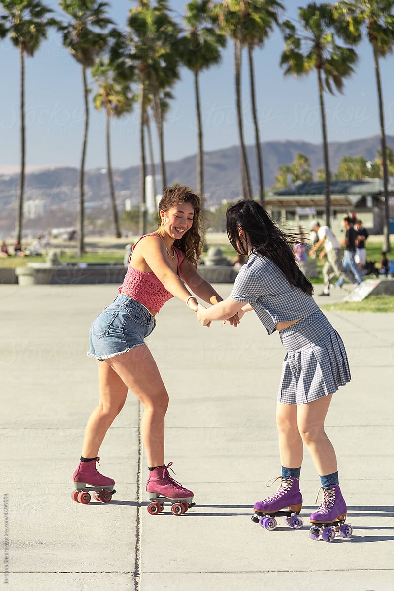 Gen-z friends having fun roller skating together by the beach