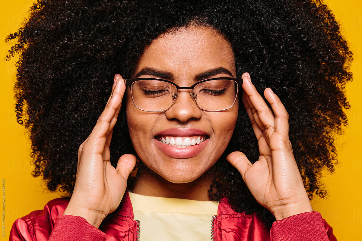Smiling afro woman putting on glasses