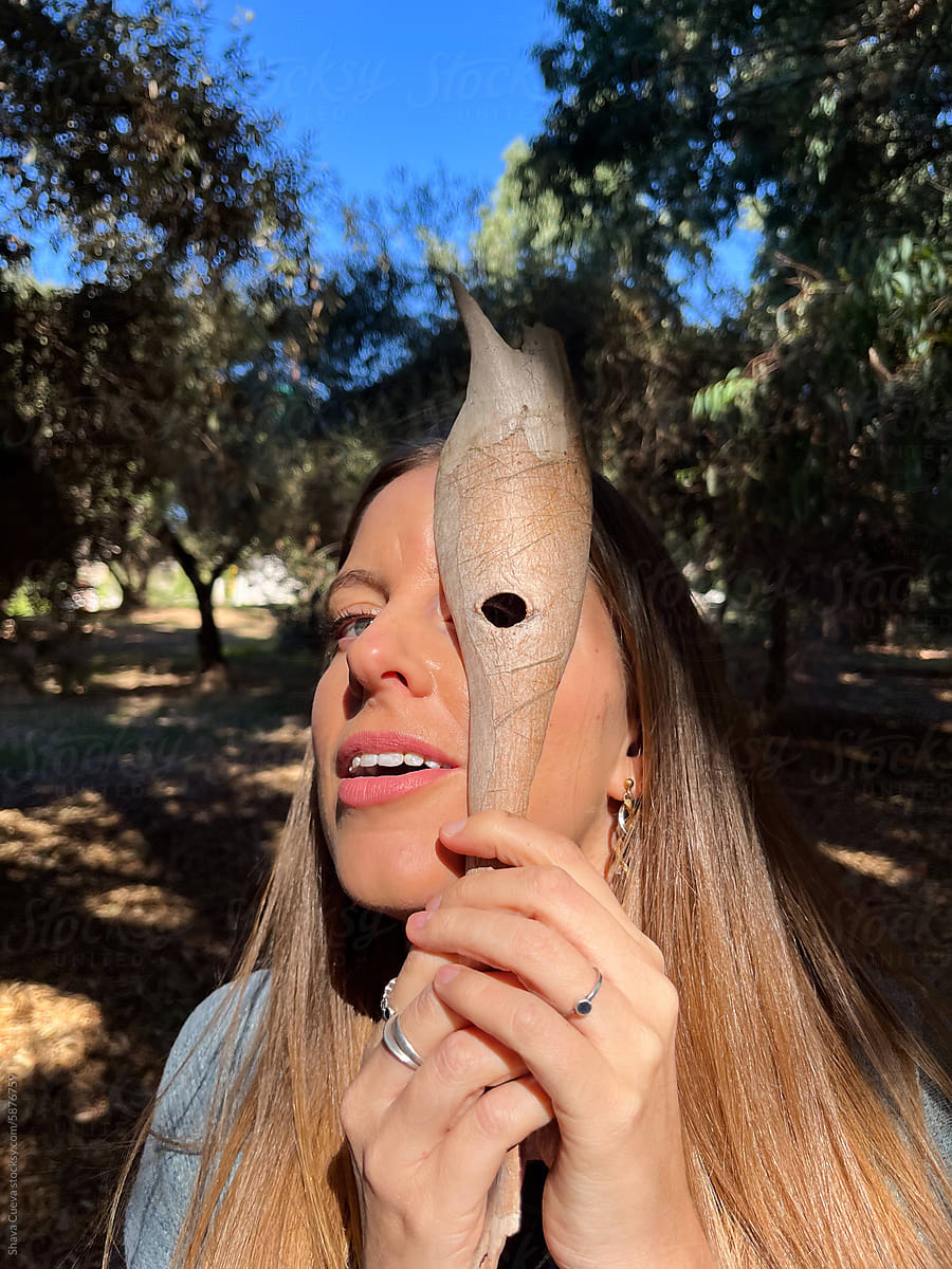A woman playing with a tree bark over her face