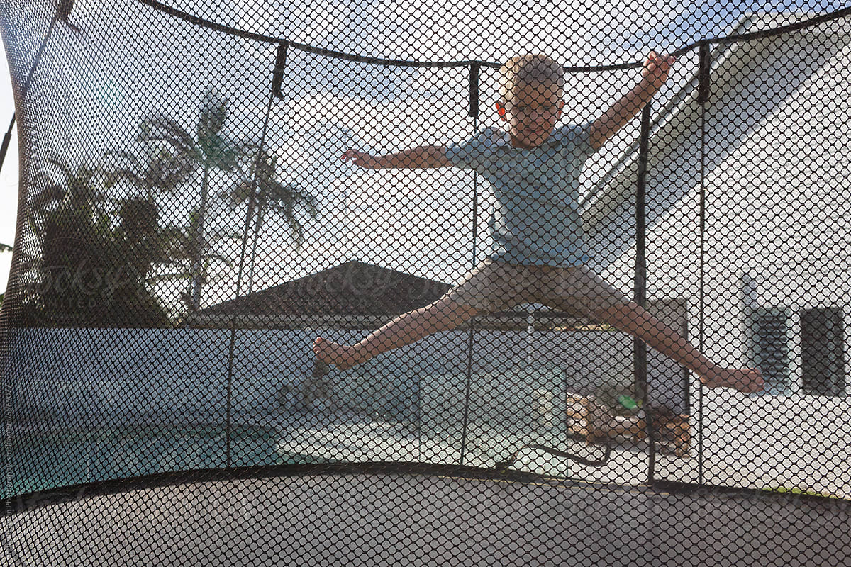 Child doing a Star jump on a trampoline