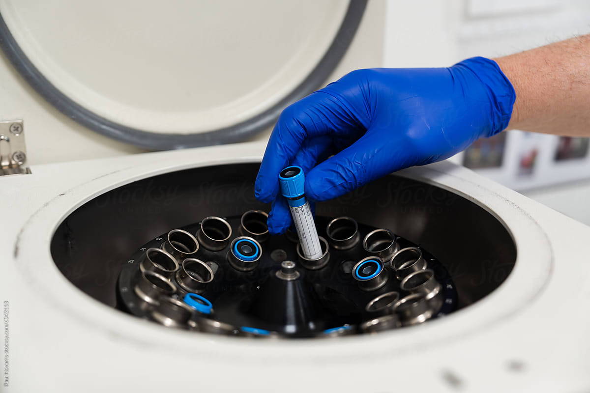 Lab technician\'s hand places a test tube in a centrifuge
