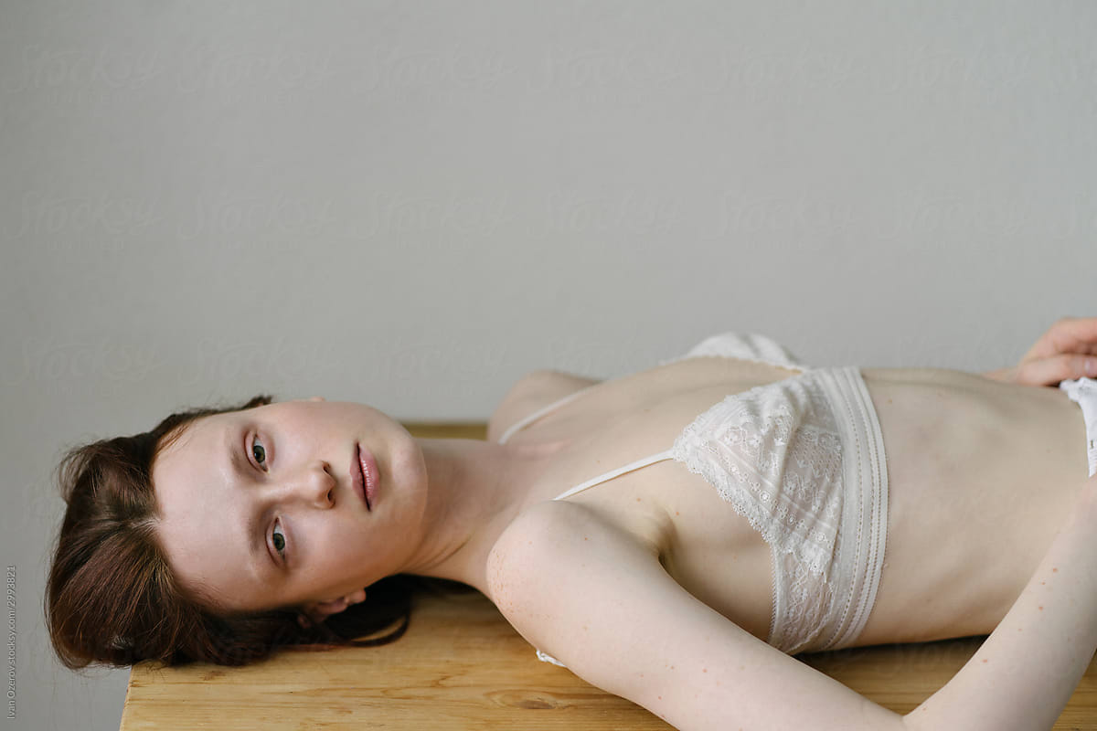 Beautiful Red-haired Model In A White Bra Is Lying On The Table by Stocksy  Contributor Ivan Ozerov - Stocksy