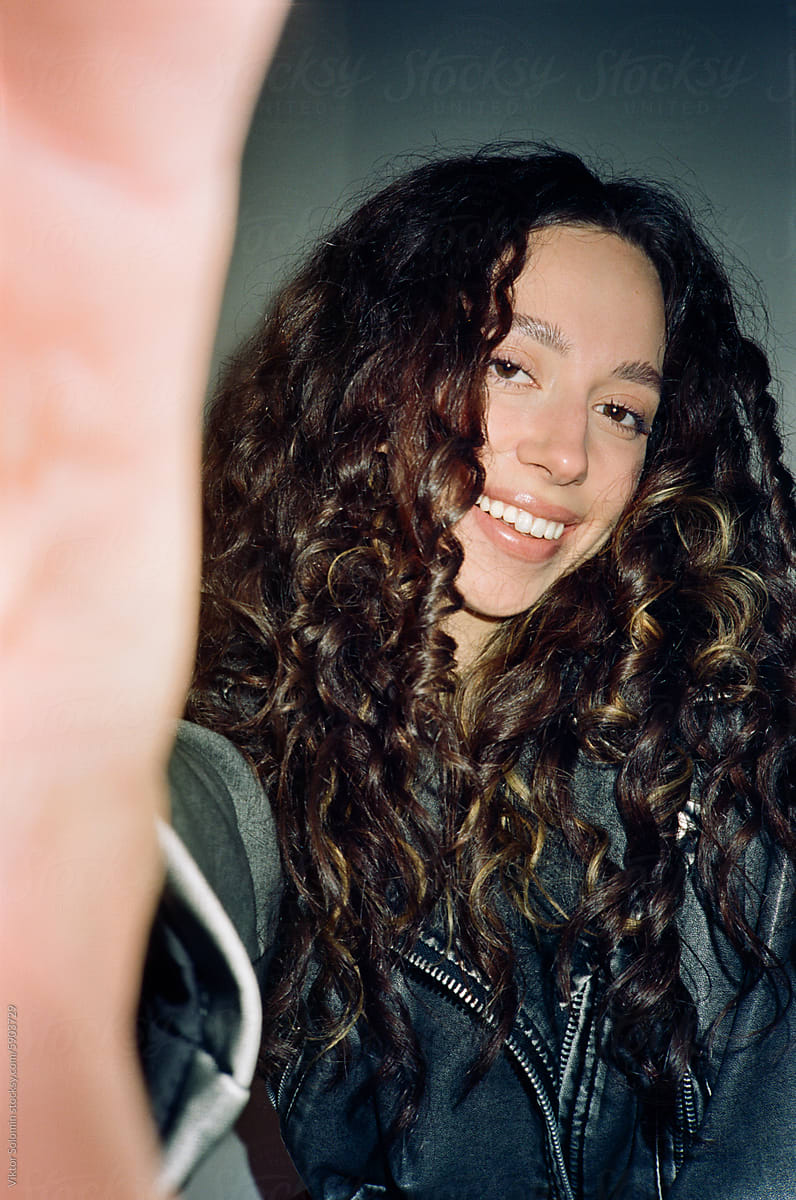 Smiling woman with long curly hair looking at camera