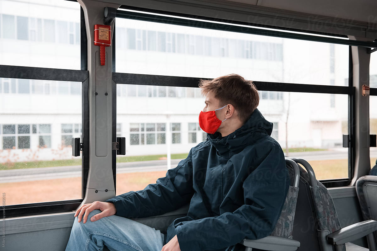Man in mask sitting near bus window