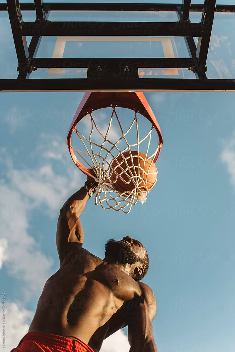 An attractive young black man playing basketball o on a sunny day