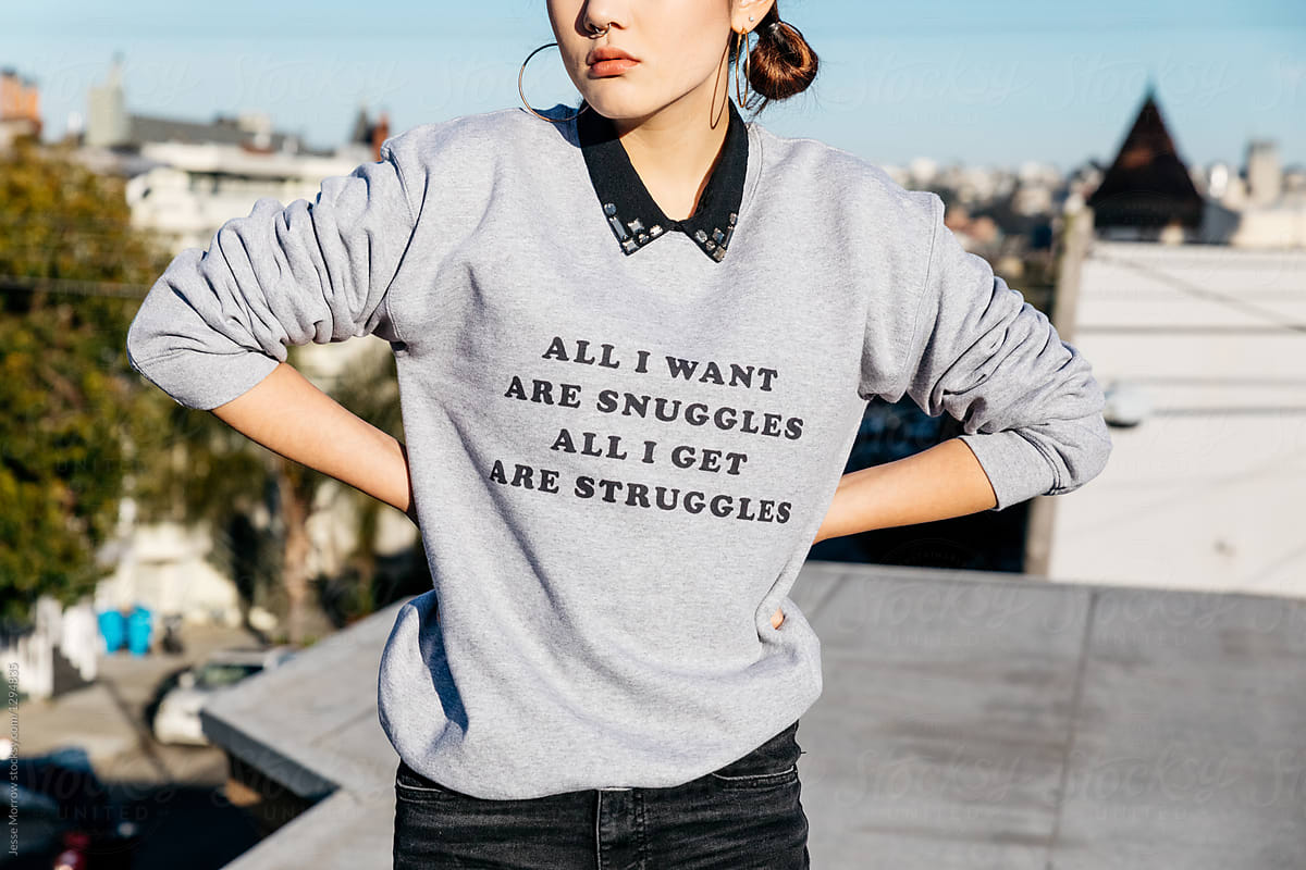 young woman on rooftop wearing ironic phrase on sweatshirt