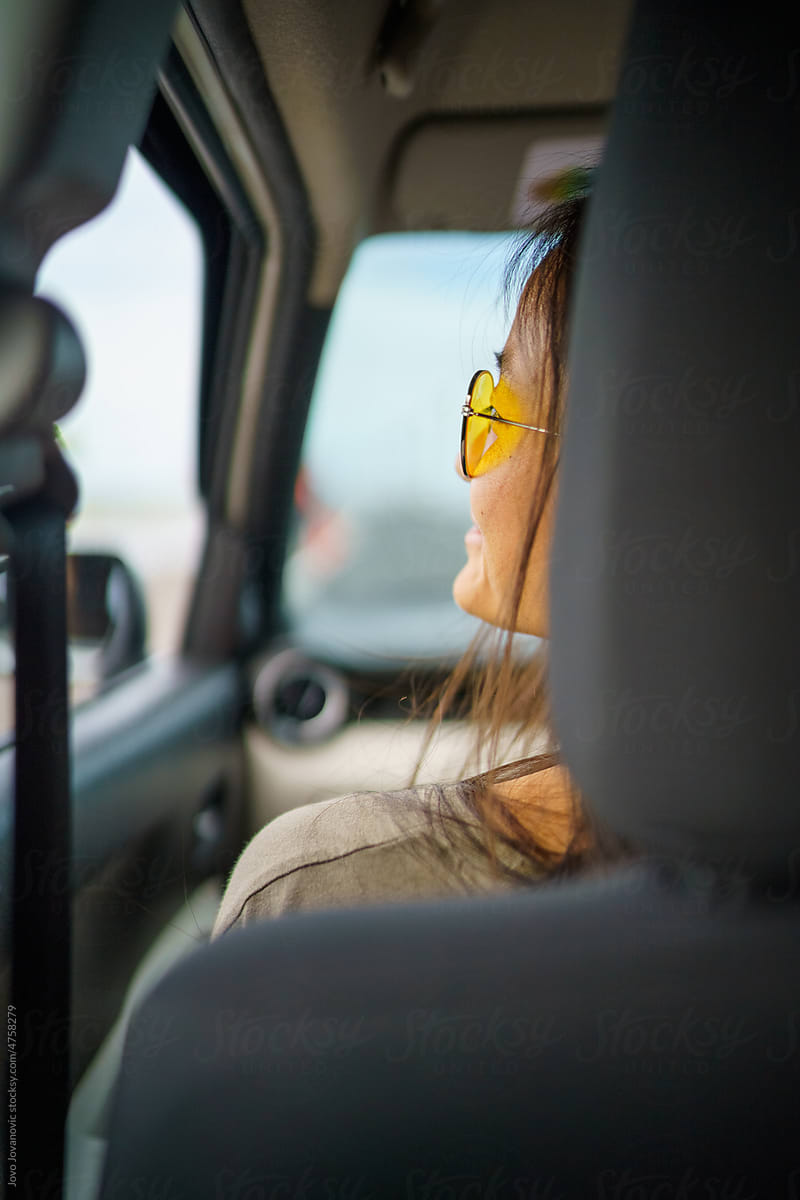 Woman with sunglasses looking out car window