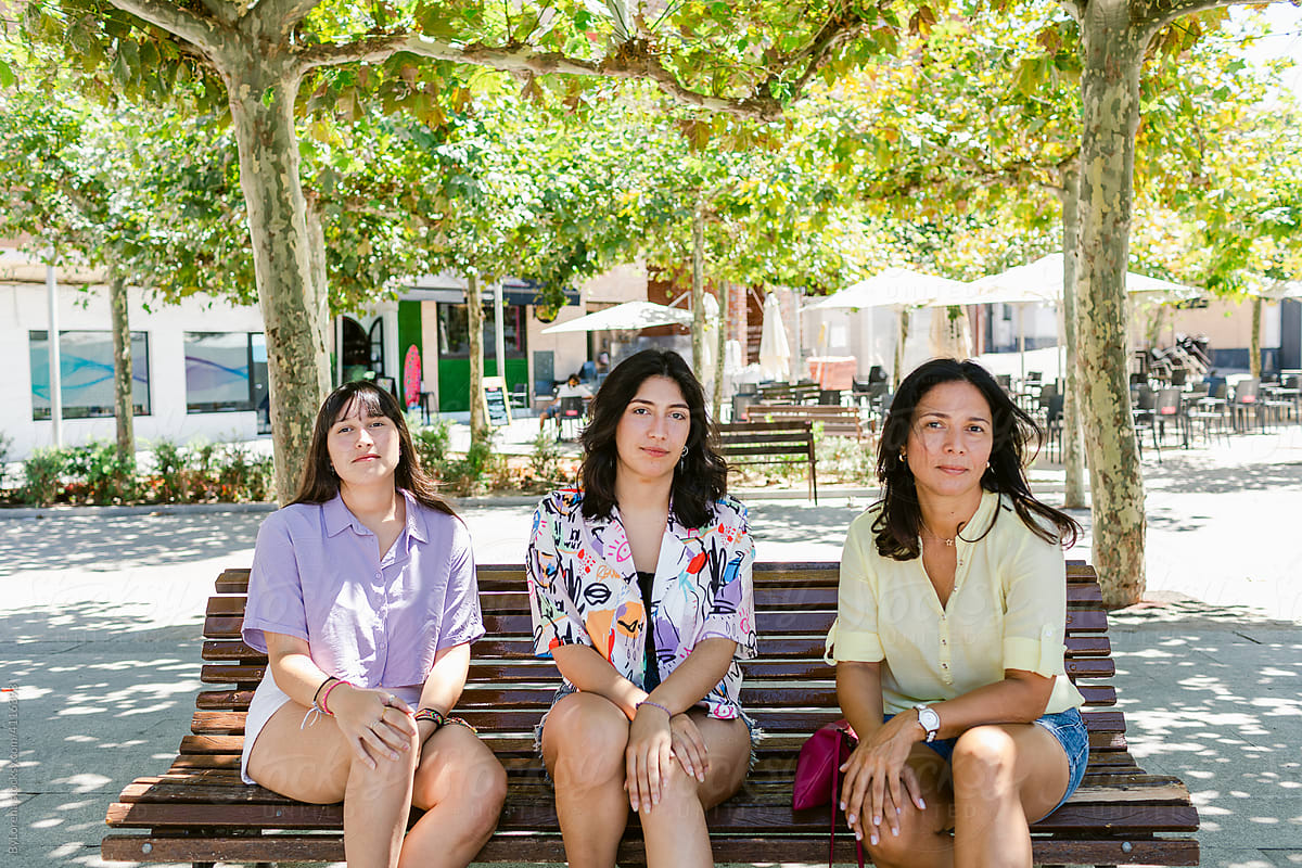 Mother and teen daughters sitting on a bench outdoors