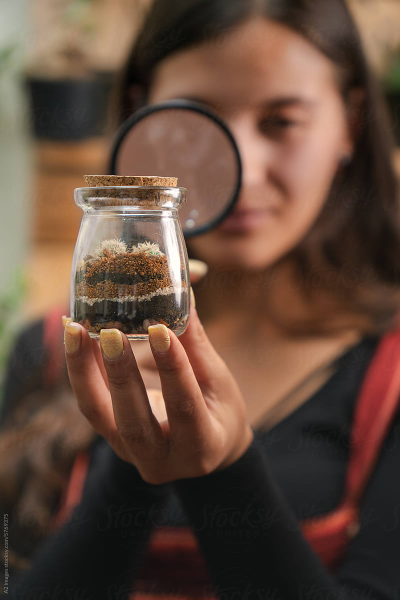Woman observing a terrarium with a magnifying glass