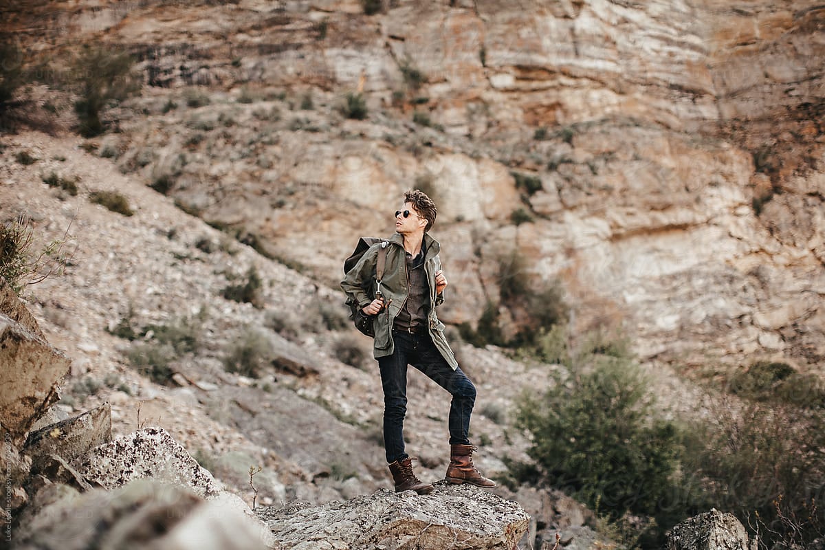 Young fashionable man hiking in desert rocks
