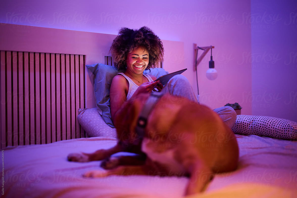 Woman resting near dog on bed