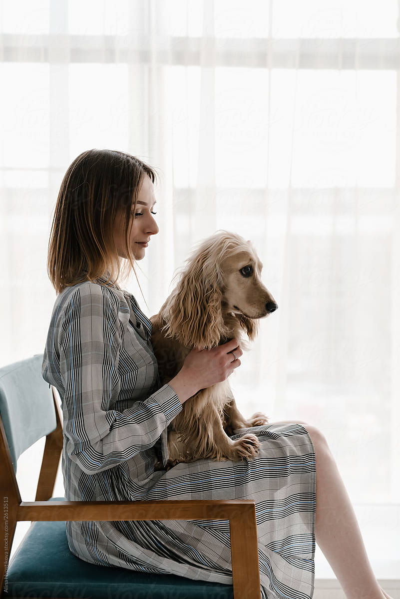 Pretty brunette girl sitting with dog on knees.