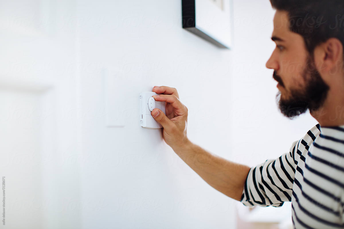 Bearded man switching thermostat at home