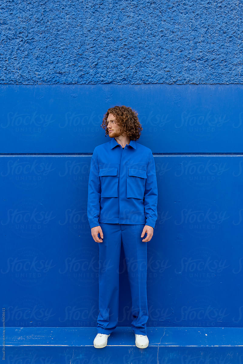Man in bright clothes against blue wall