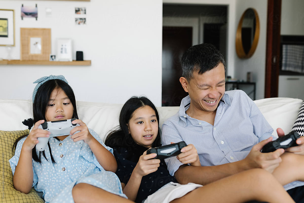 Father and two daughters paying video games at home