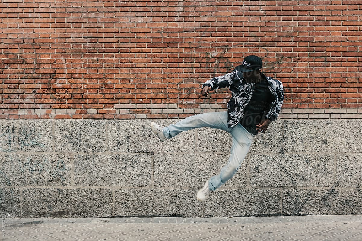 Black Man Jumping Besides a Brick Wall