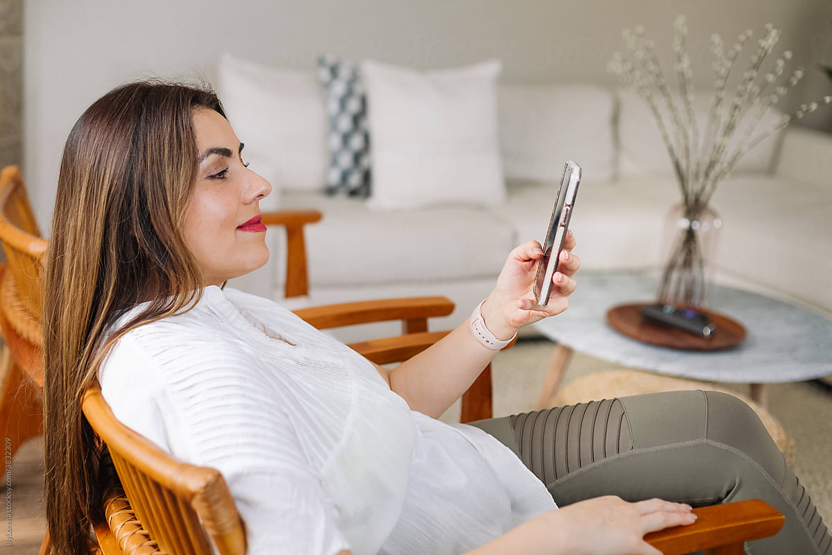 Smiling woman scrolling smartphone at home