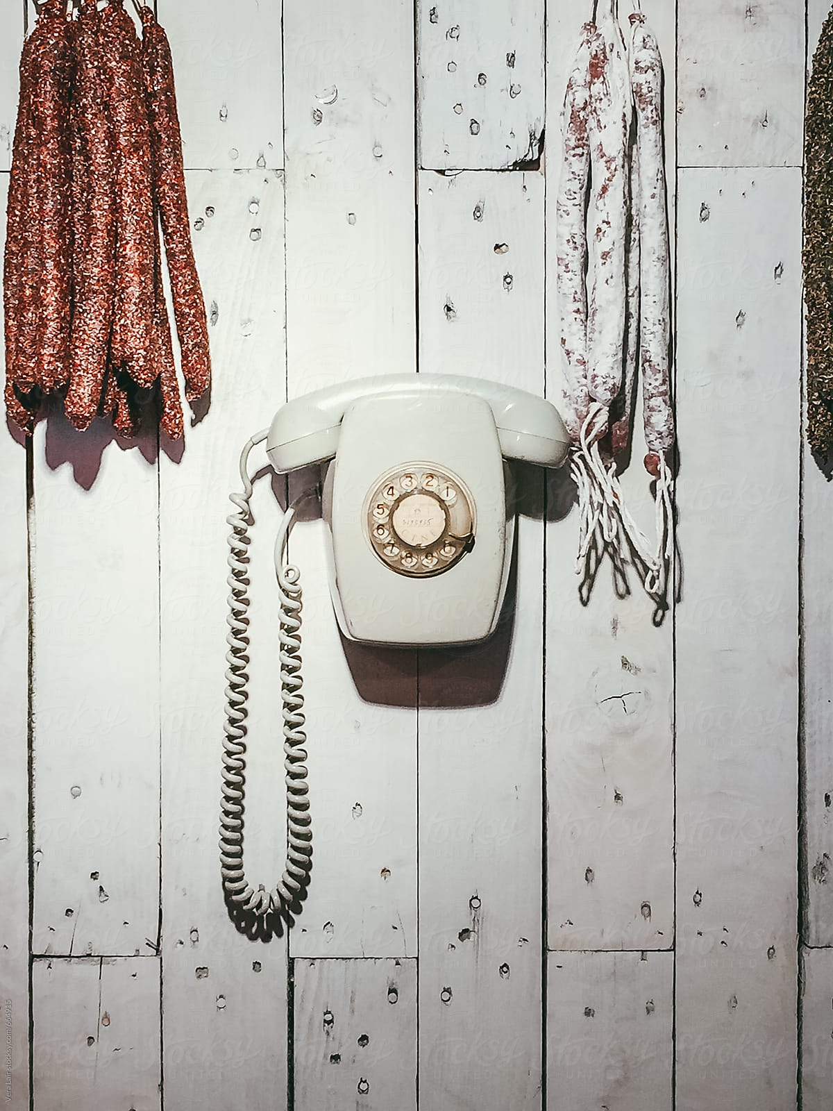 Old phone and sausages hanging on a wall