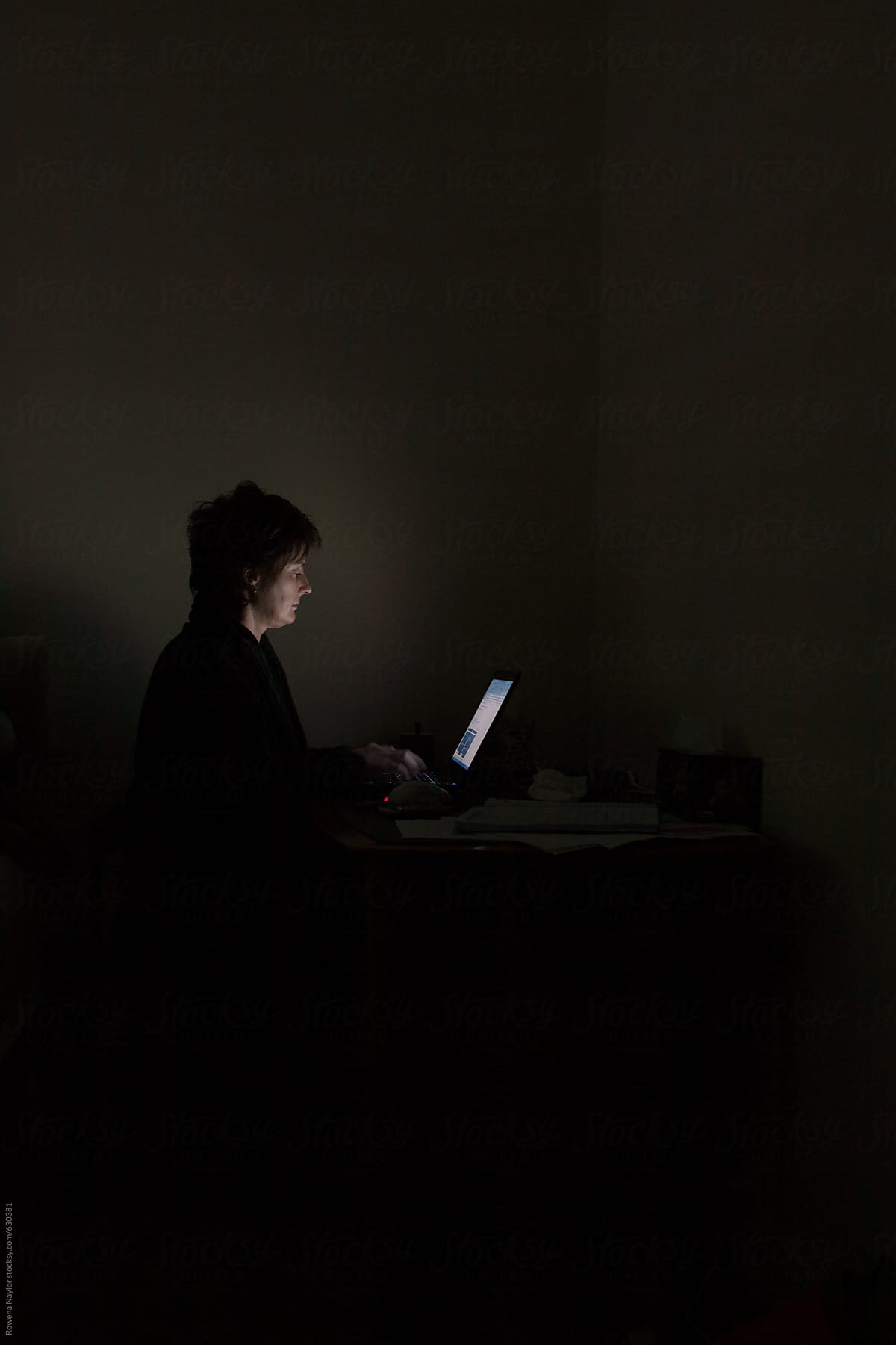 Woman using laptop in dimly lit room
