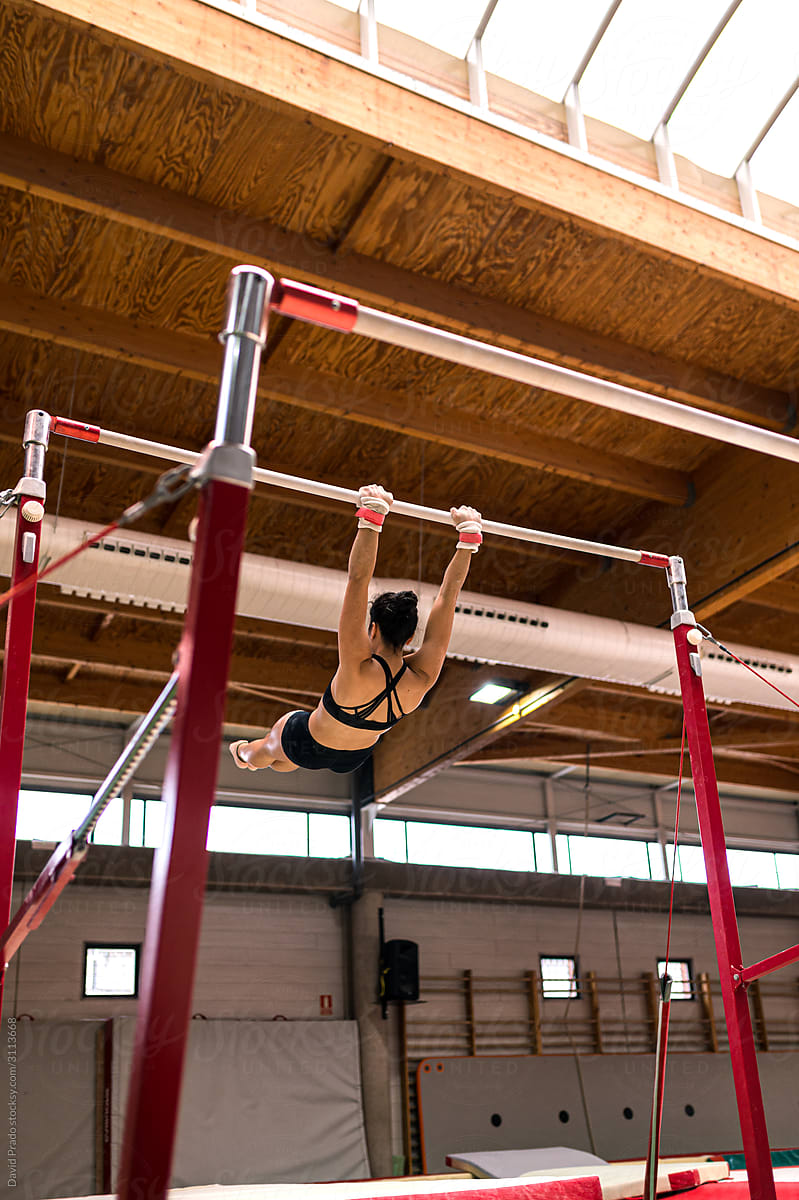 young artistic gymnast woman performing and training uneven bars