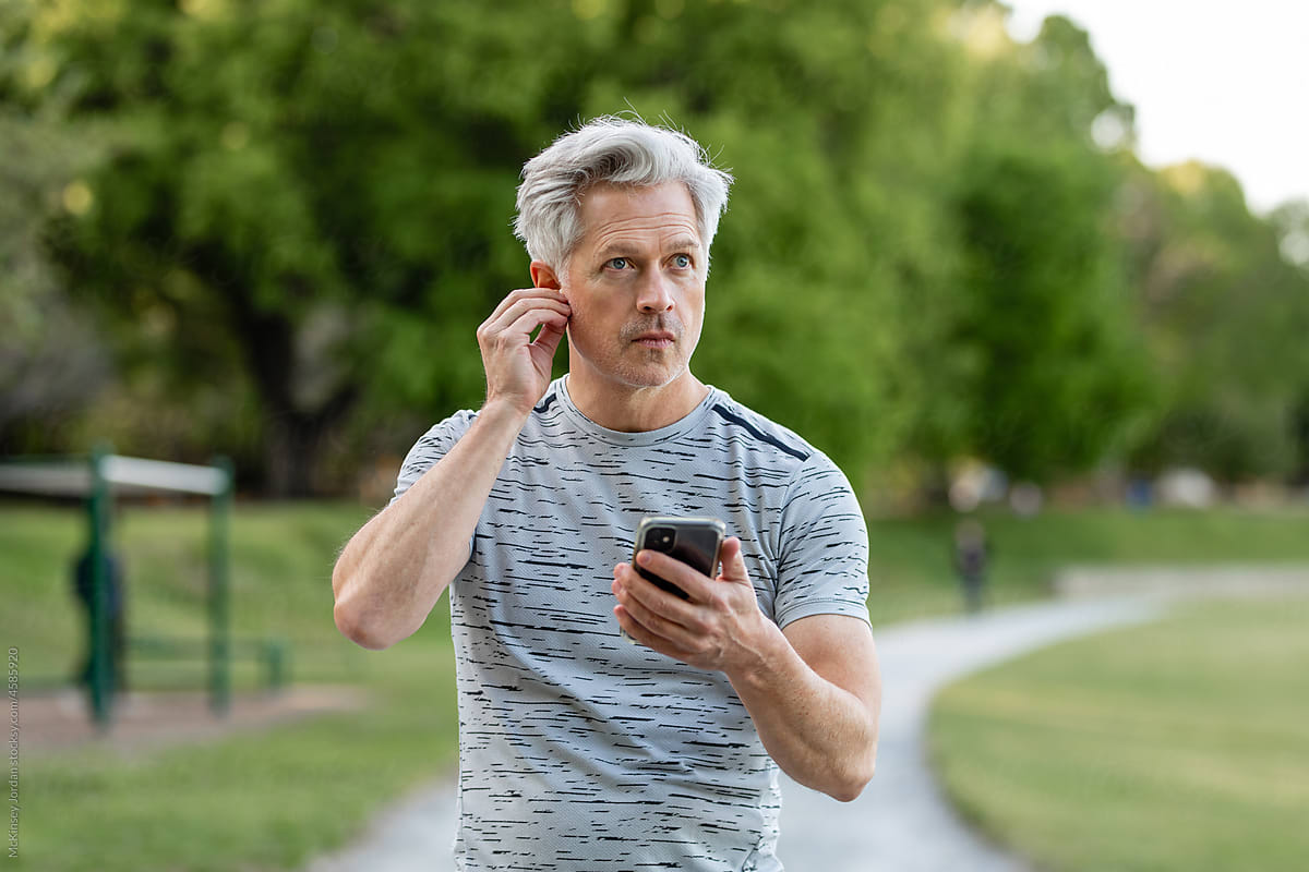 Fit Man Puts Earphone In To Listen To Music While Working Out