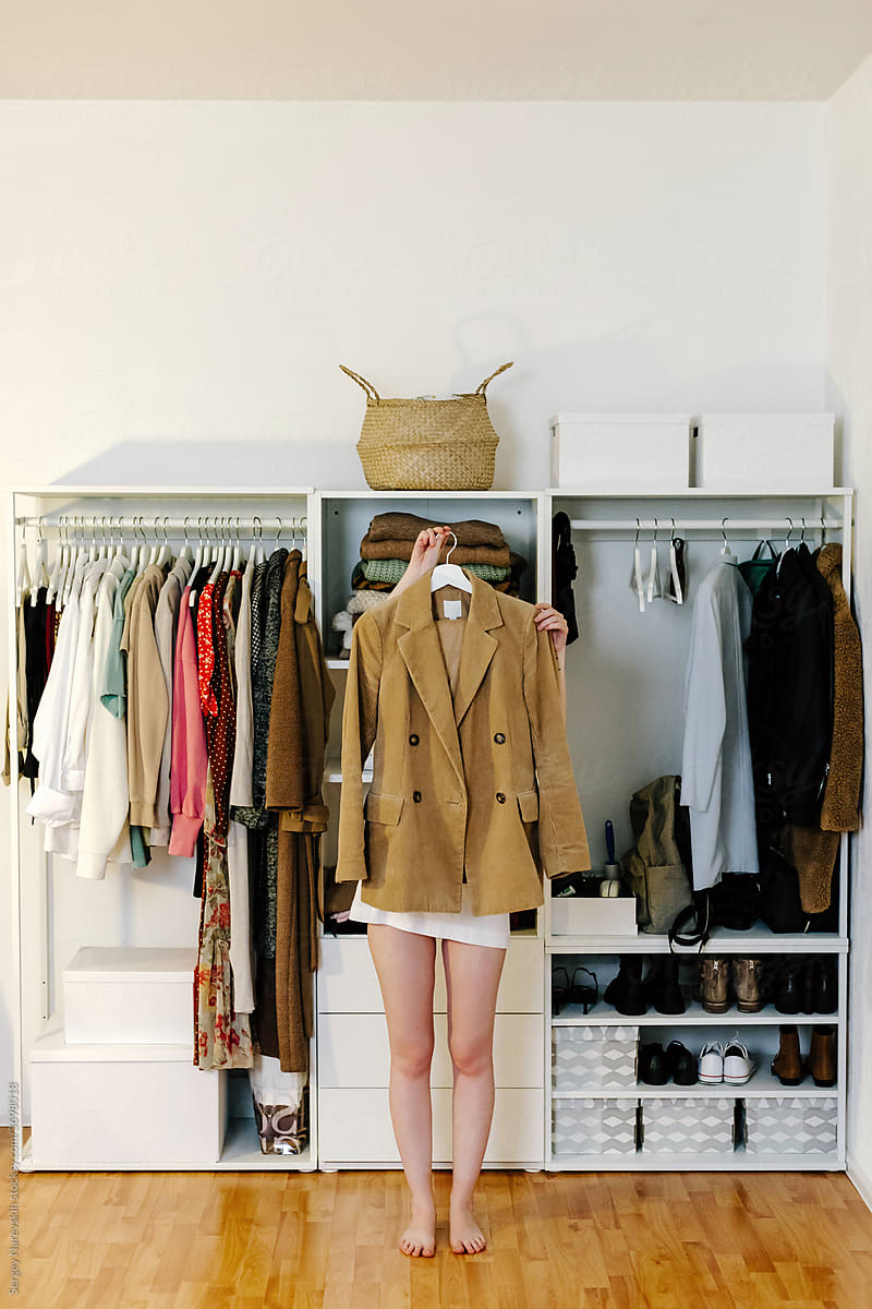 Unrecognizable woman standing with stylish jacket near wardrobe