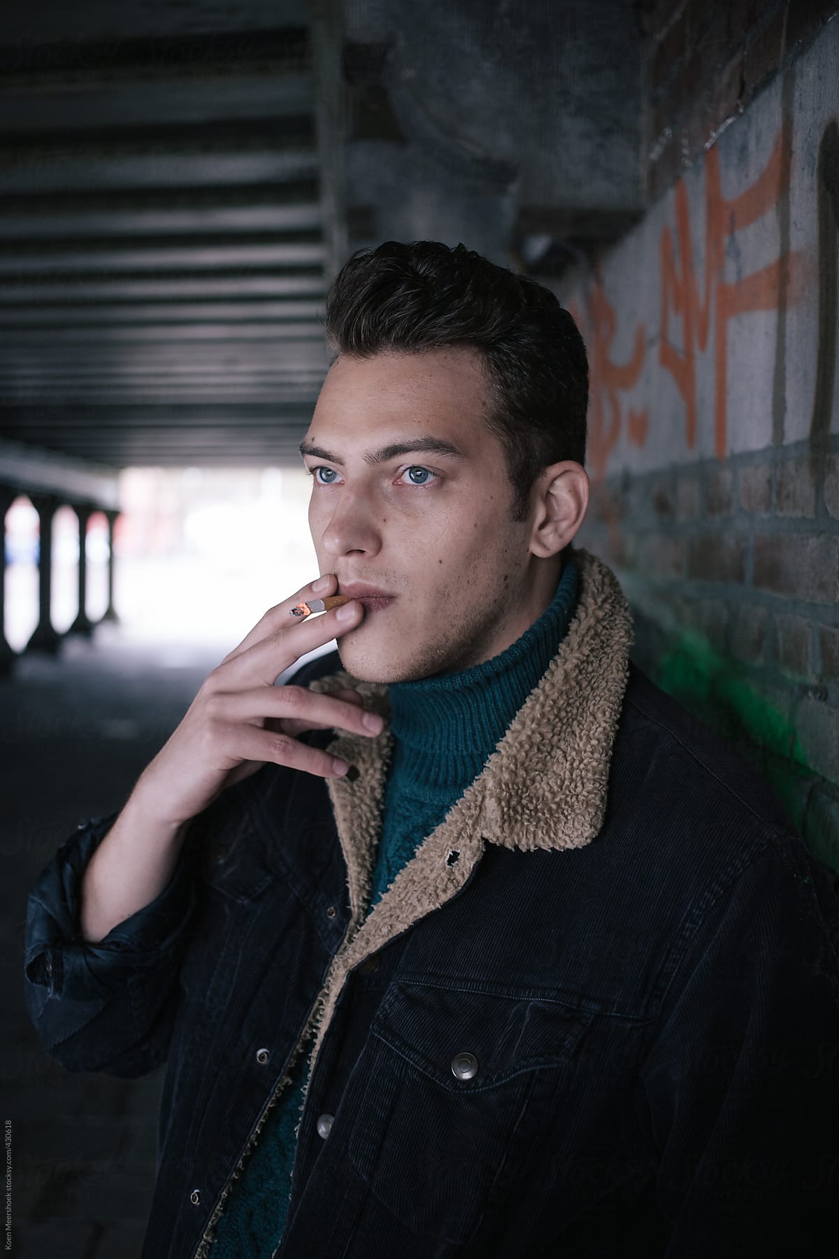 Young Handsome Man Smoking Under A Bridge.
