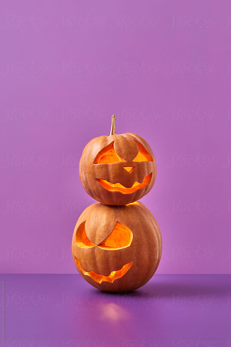 Glowing carved pumpkins on purple background.