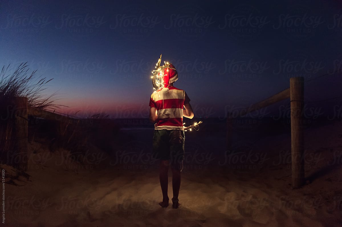 Boy carrying driftwood decorated with Christmas lights
