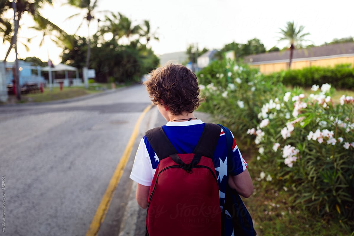 Boy with a red back pack walking along a road in Antigua
