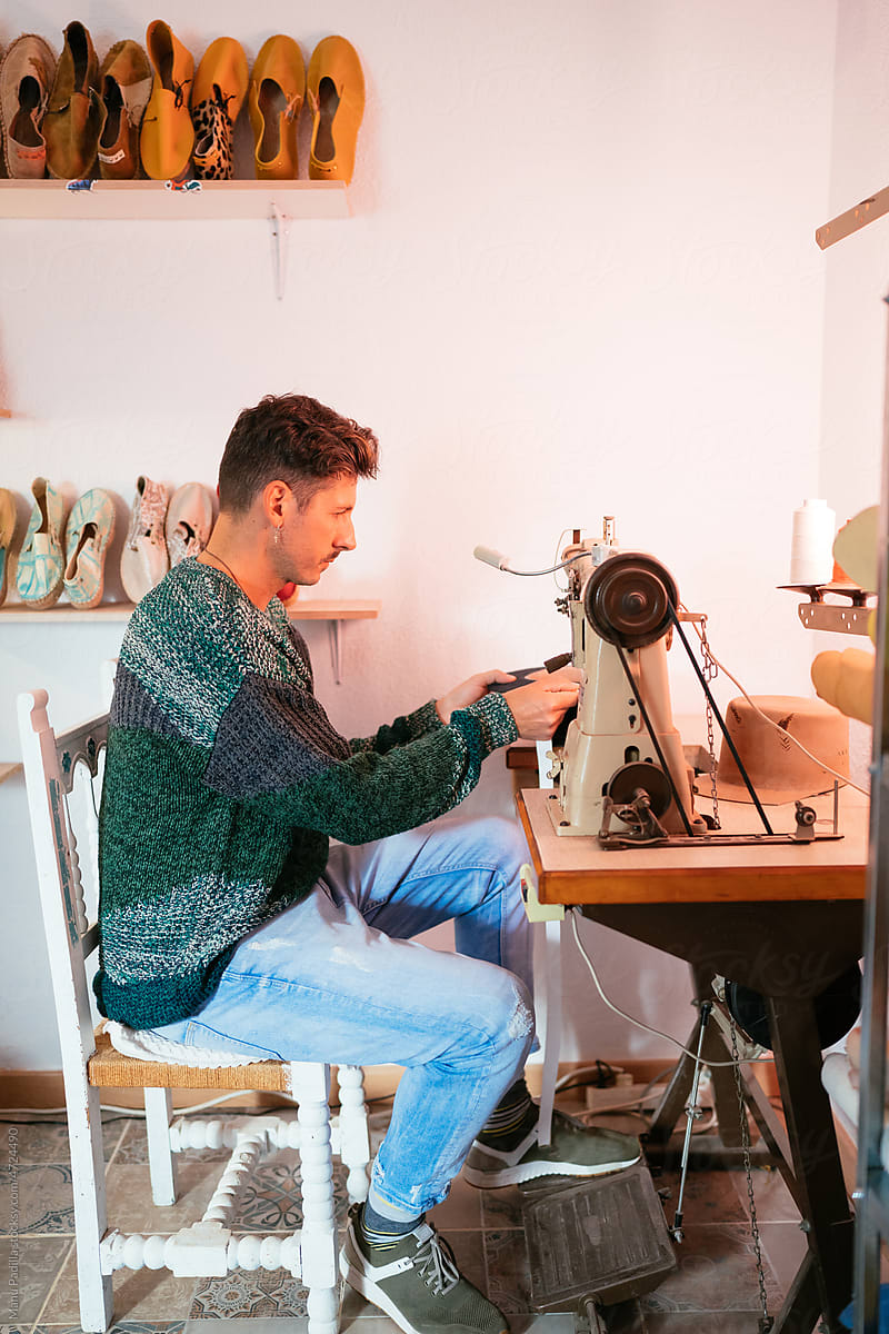 Talented male tailor sewing hat on machine in atelier