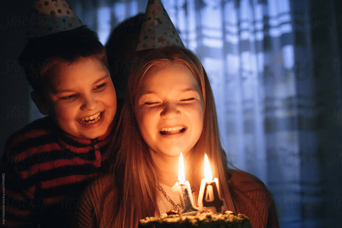 Teenager girl celebrating 14 Birthday, blowing out candles on cake