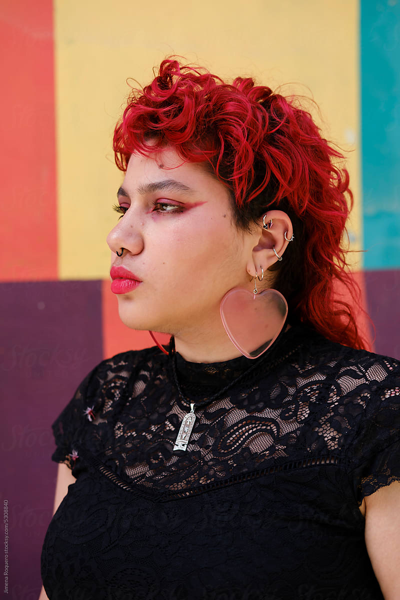 Red hair person with pierced ears in front of colorful wall