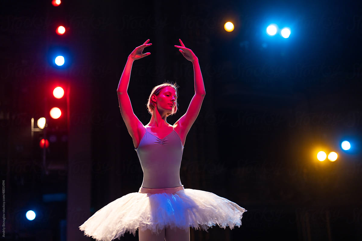 Caucasian brunette ballerina girl performing dance around neon light