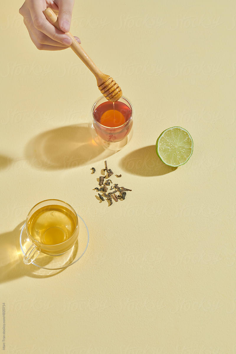 Tea with lemons and honey, shot from above on light yellow background