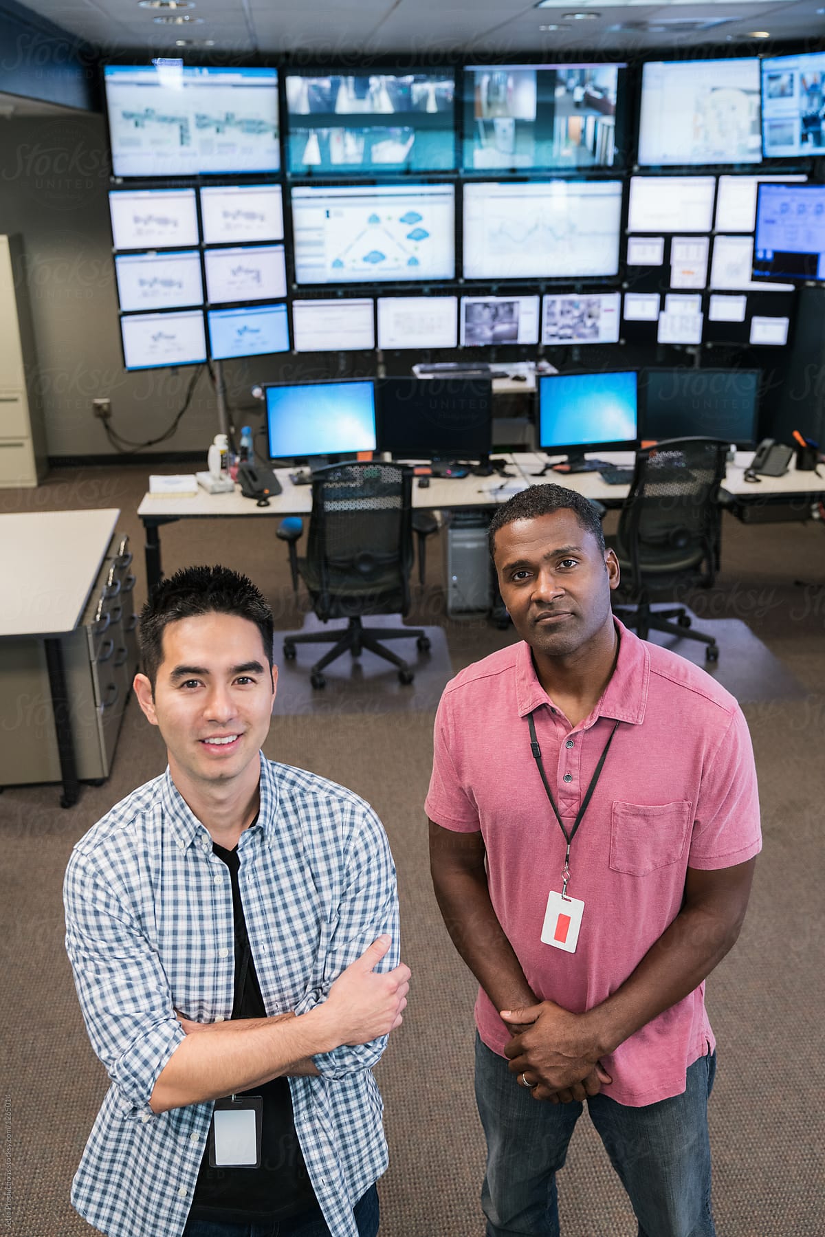Portrait of two smiling technicians in server room monitoring ce