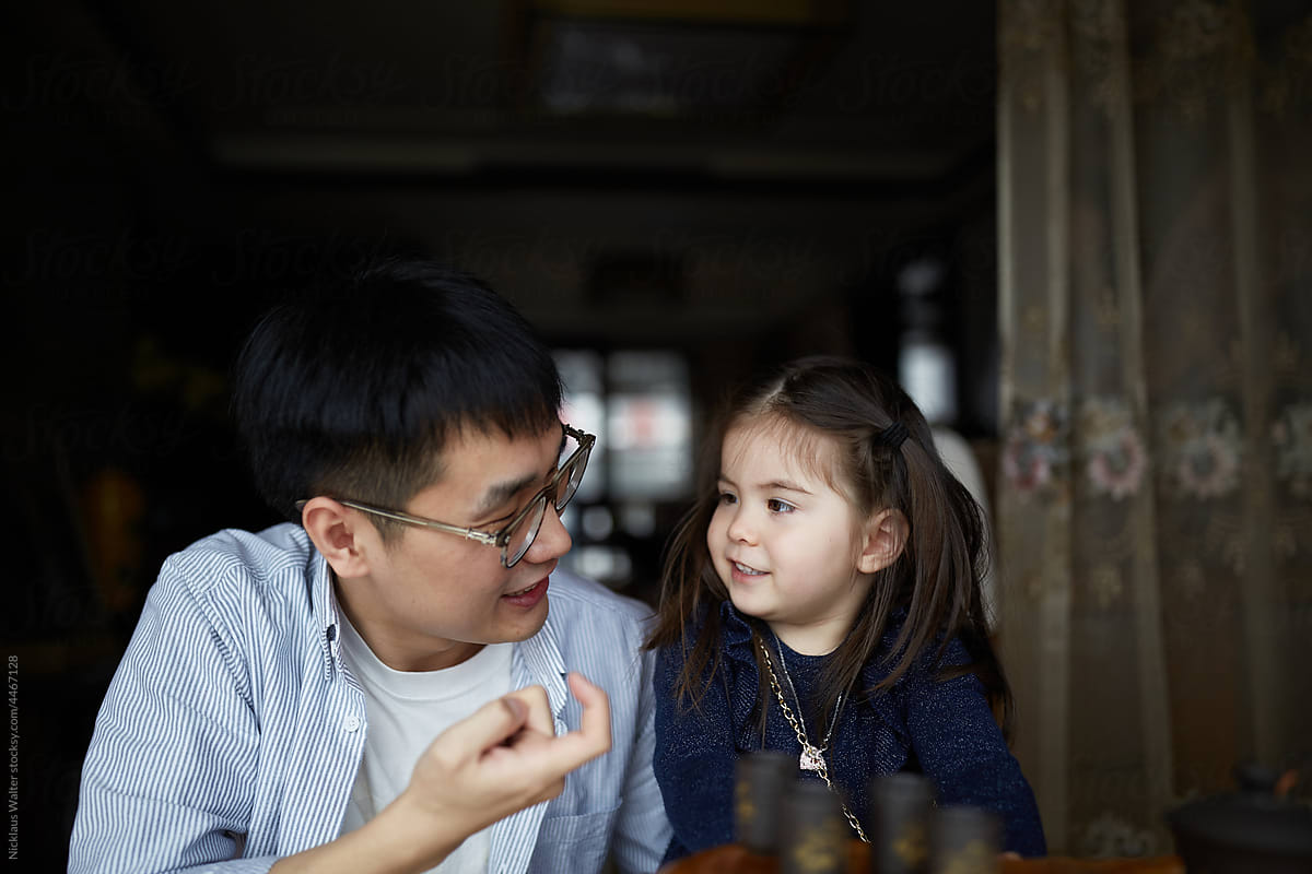 Chinese Father And Multiracial Daughter Play While Drinking Tea.