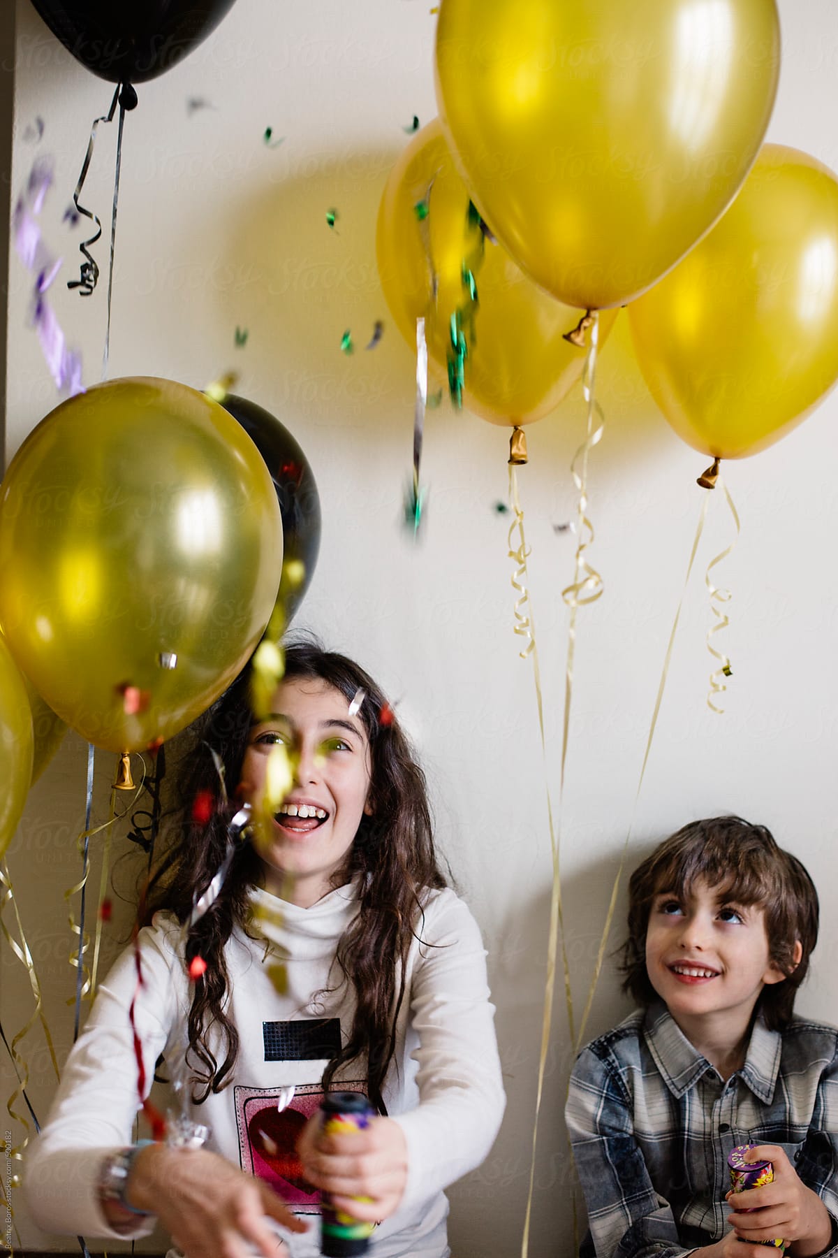 Boy and girl are happy and laughing at a party with balloons and confetti