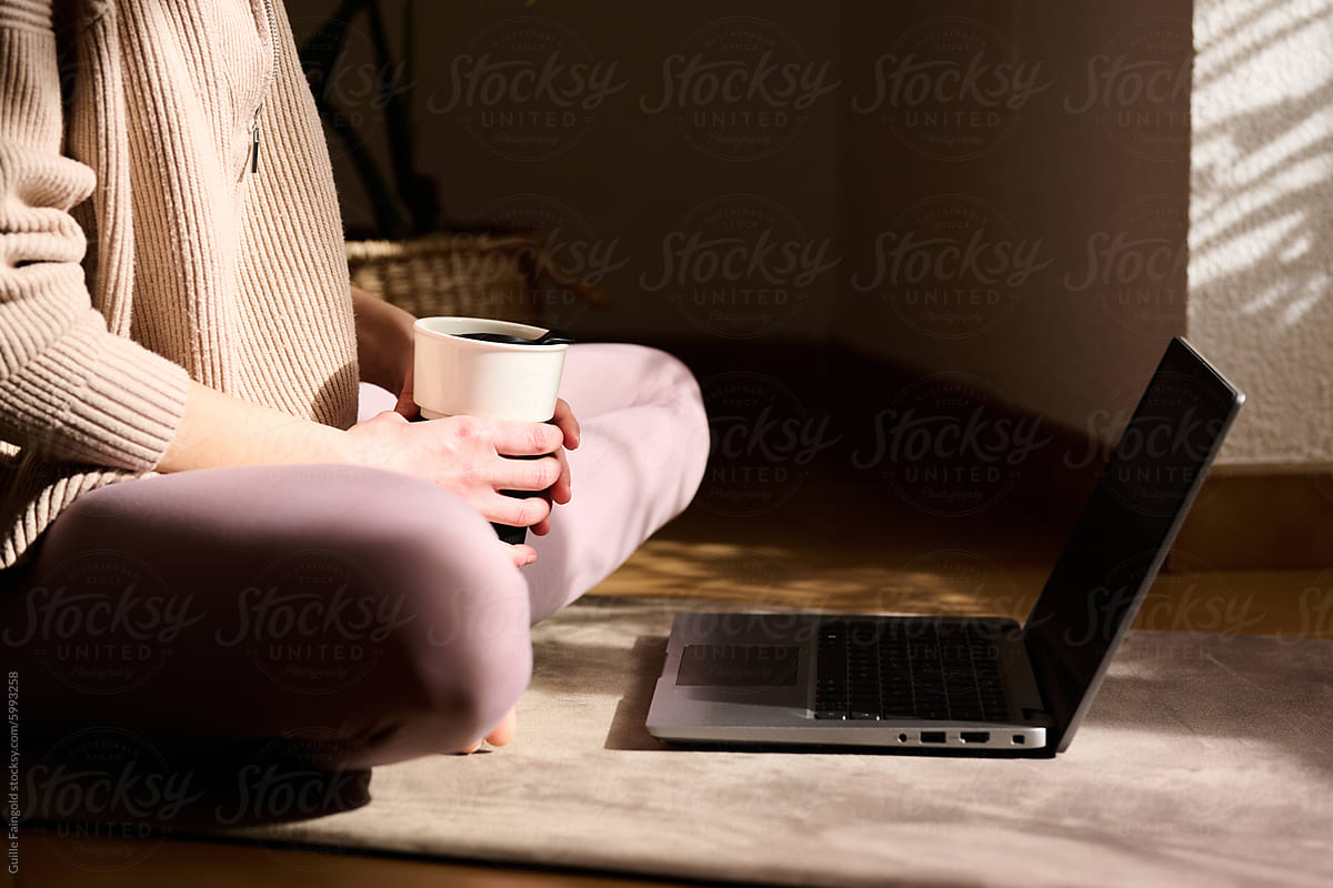 woman with Coffee Cup Using Laptop on Floor