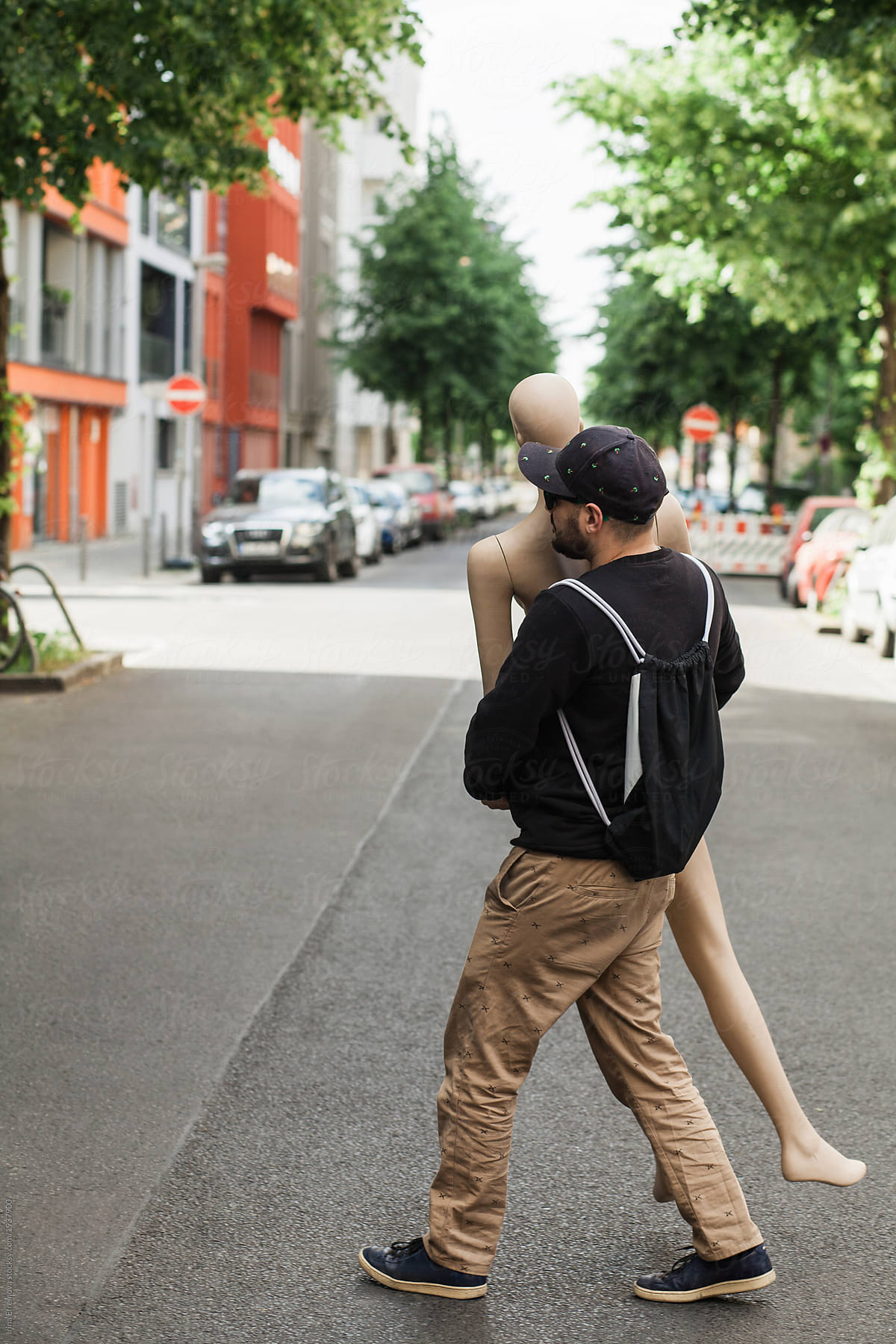 Man on a street carrying an artificial woman