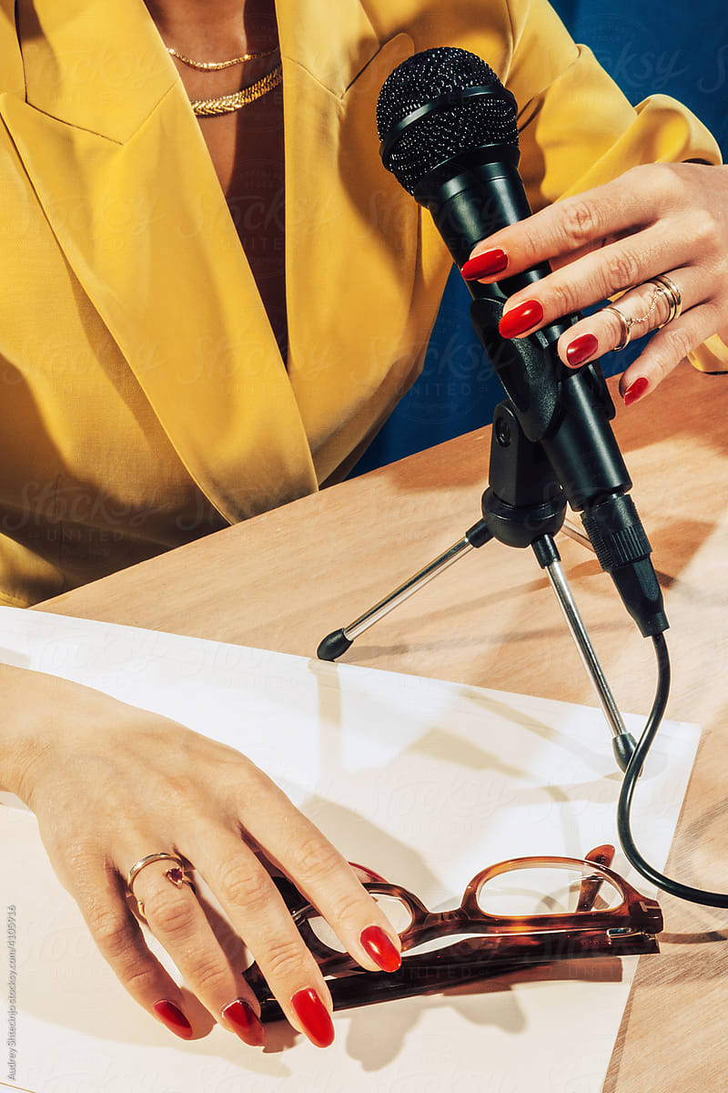 Female hands holding microphone in studio .