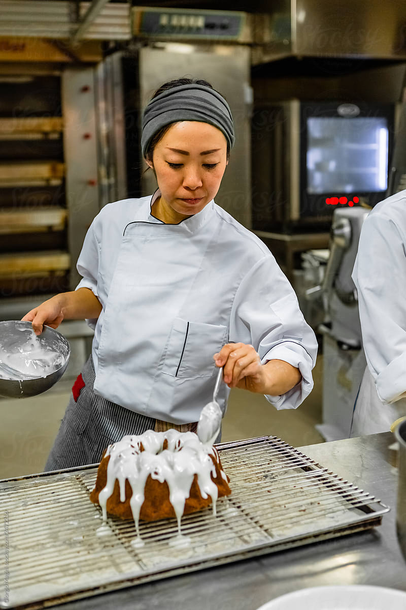 Young Chef Frosting a Chocolate Cake in a Professional Kitchen