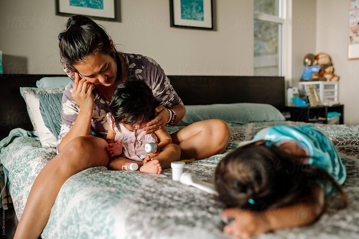 Stressed mom on bed with young daughters