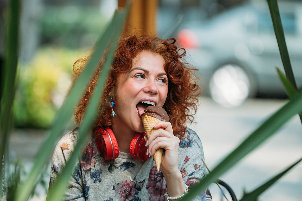 Cheerful woman eating delicious ice cream on street