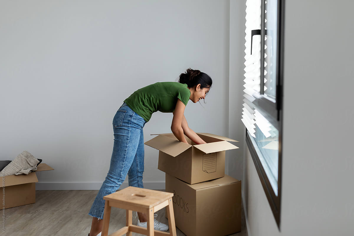 Woman unpacking moving boxes at new home