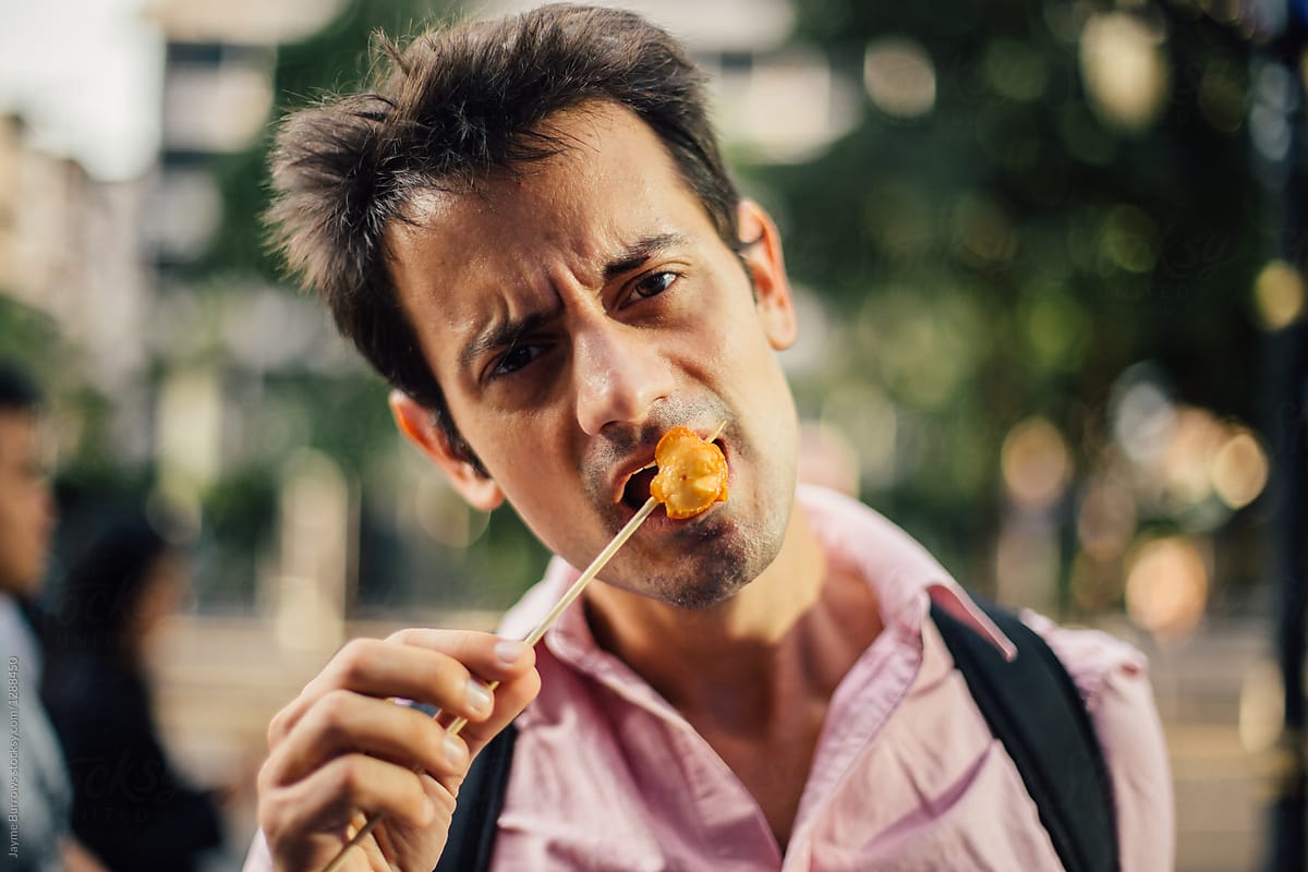 Man Eating a Piece of Chicken from Street Food Vendor