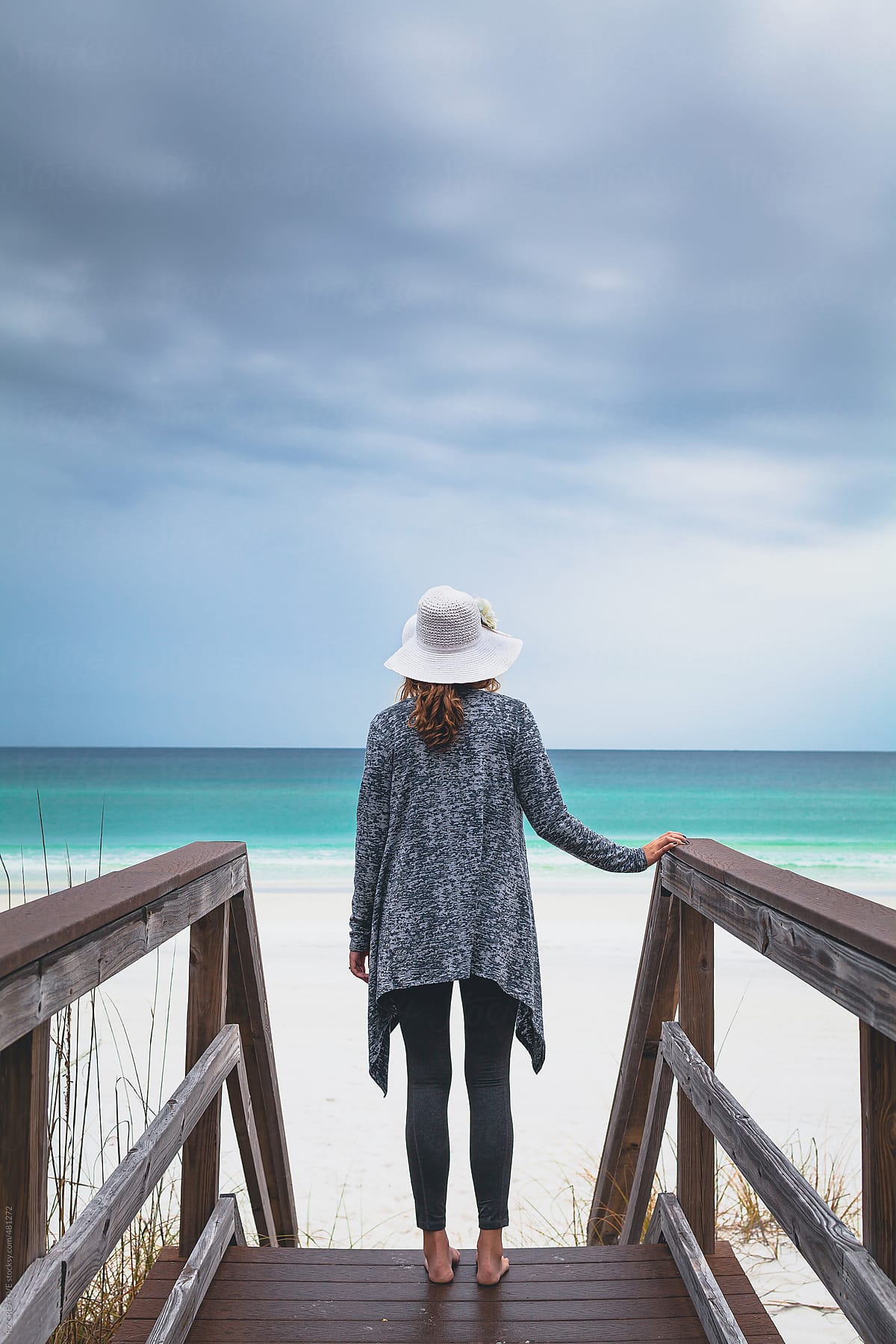 Woman on boardwalk at stormy beach.