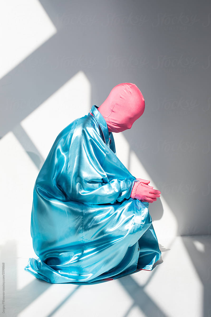 Incognito person in colorful outfit sitting in studio