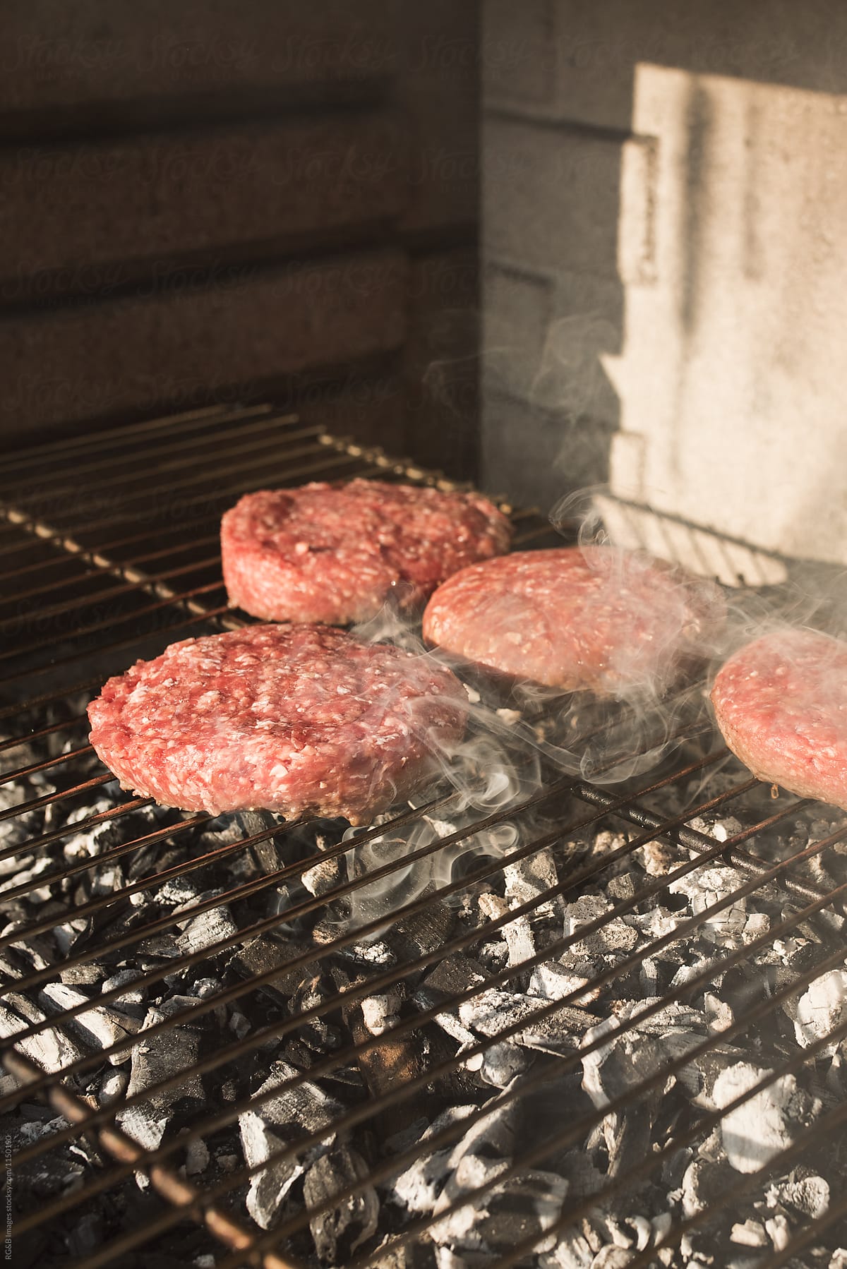 Meat burgers getting cooked on the grill outdoor