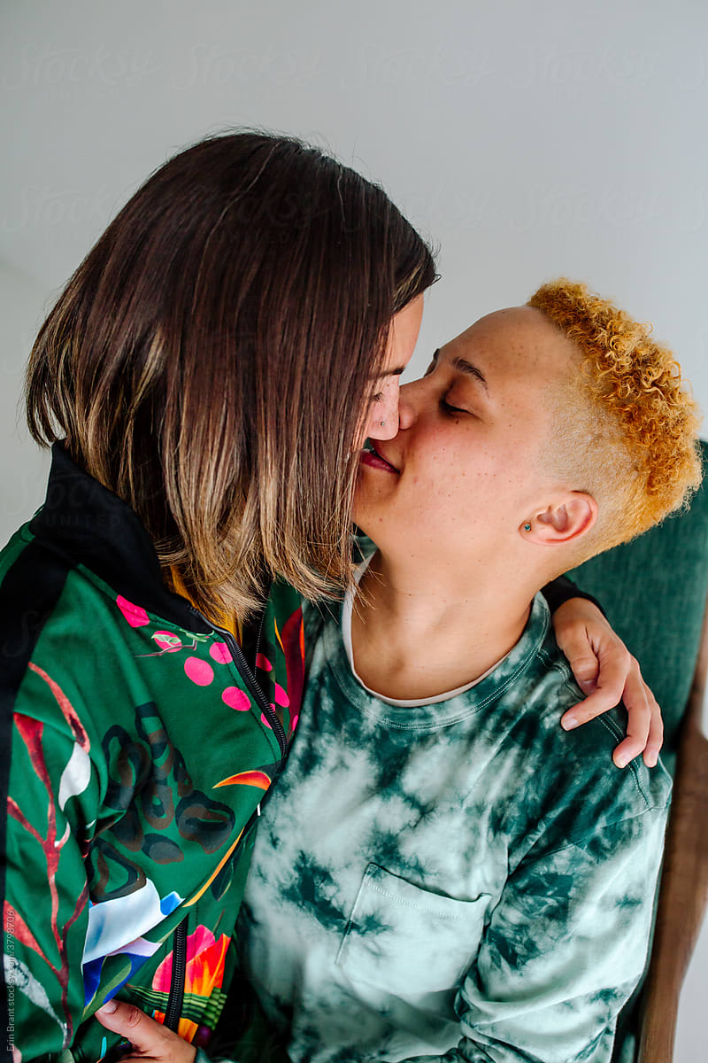 Lesbian couple kiss while sitting in chair